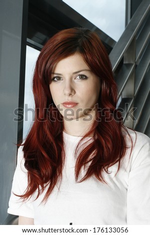beautiful young business woman with red hair on a office stairs