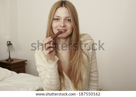 Image of a blond beautiful girl similar to a famous hollywood actress eating chocolate