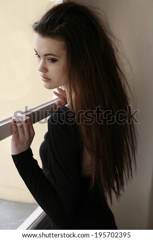 woman looks through the window , dreamy romantic girl stares out of the window , beautiful girl in the window