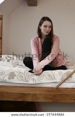 picture of a girl on the bed happy dreamy beauty girl hugging her legs while siting in bed against the wooden wall