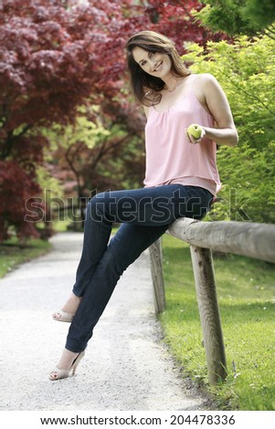 Young beautiful woman walking on the path in the park next to the fence , beautiful woman walking on the road in a beautiful park