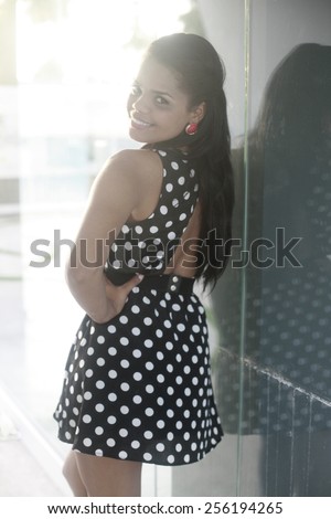 image of a smiling girl posing on glass background, outdoor portrait latin girl dressed in black and white dots dress at the beach posing on white background , fashion photo of sensual beautiful woman