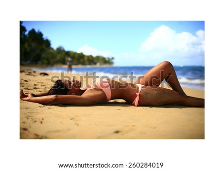latin girl dressed in bikini at the beach posing in the water , fashion photo of sensual beautiful latin woman with dark hair posing in water on summer beach in sunlight rays