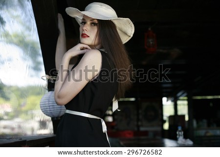 young lady with white hat on the river boat looks down  young beautiful woman on a river boat posing dressed in brightly colored clothing,