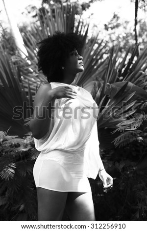 beautiful latina in with afro hairstyle in white mini dress standing in nature black and white photography