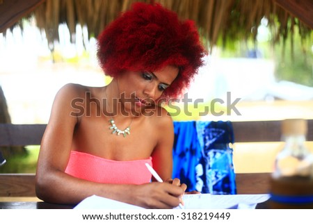 Latin young woman writing. Girl with red afro hair style writing letter