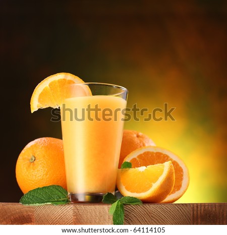 Still life: oranges and glass of juice on a wooden table.