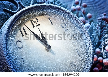 Christmas clock over snow wooden background. Five to twelve.