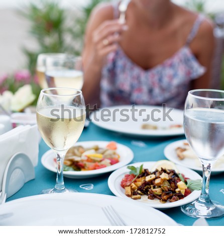 Romantic dinner with white wine. In the background a girl is out of focus.