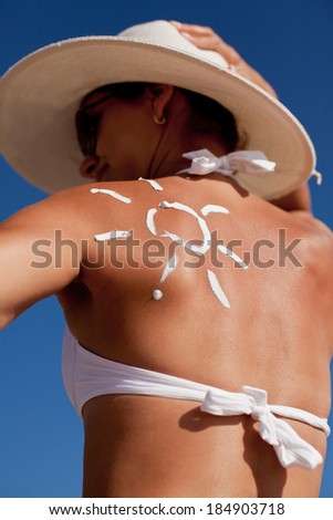 Tanning lotion in the shape of sun on woman\'s shoulder.