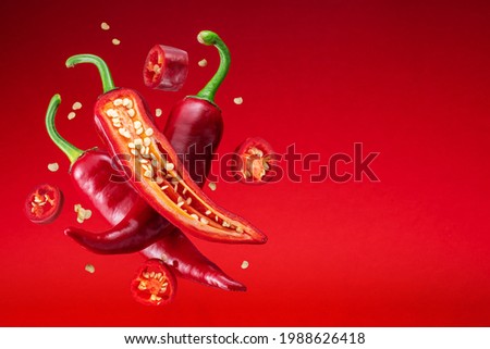 Fresh red chilli peppers and cross sections of chilli pepper with seeds floating in the air. 商業照片 © 