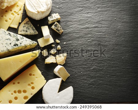 Different types of cheeses on black board.