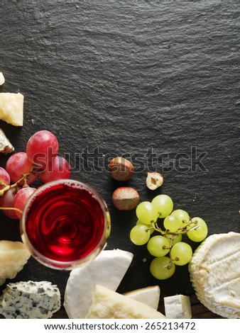 Different types of cheeses with wine glass and fruits. Top view.