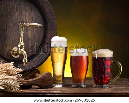 Still life: old wooden pin of beer, glass of beer and wheat on the table in the cellar.