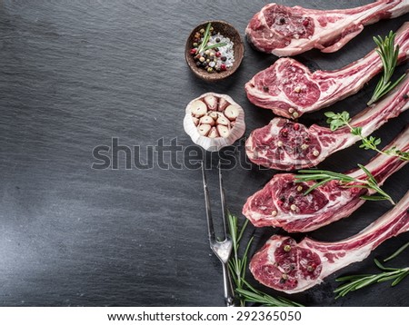 Raw lamb chops with garlic and herbs on the old wooden table.