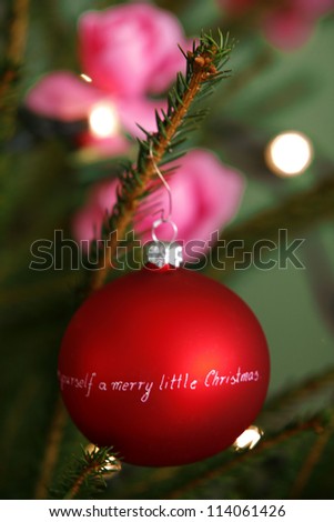 Christmas decorations: bright red ball with wish written on it on a christmas tree