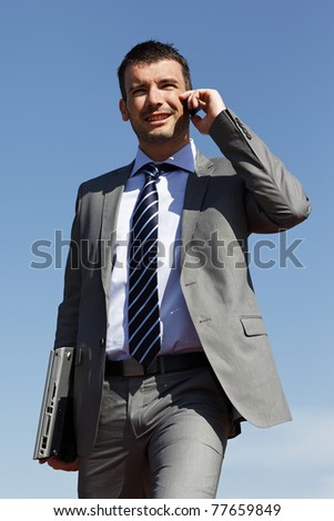 young businessman with phone and blue sky