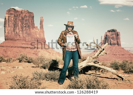 blond cowgirl holding wanted paper at Monument Valley