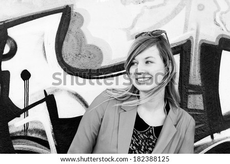 Beautiful young woman smiling at the graffiti wall