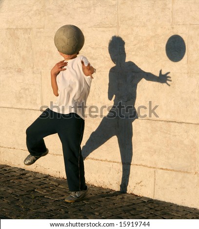 Boy playing catch with his shadow near the wall. Lisbon, Portugal