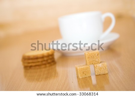 Cup of tea or coffee, sugar and biscuits. Focus on the sugar