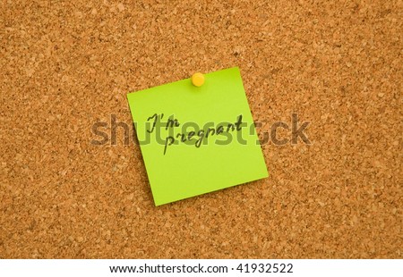 Adhesive paper note on cork board with words I am pregnant
