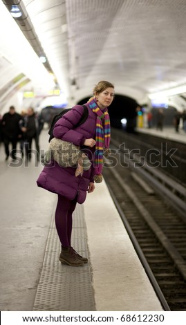 Tourist girl in bright clothes and funny bag waiting for the train in Parisian metro