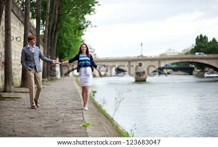Couple is walking by the Seine embankment in Paris