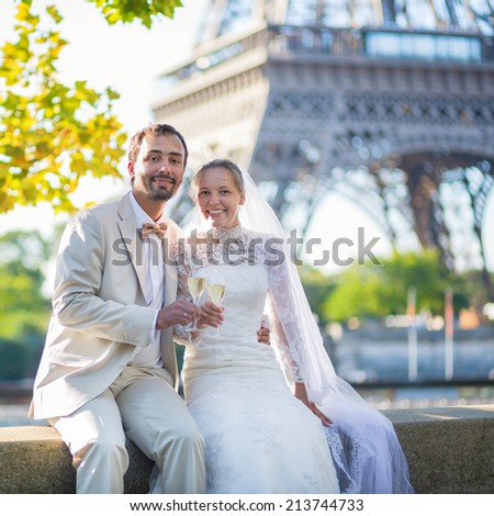 Beautiful just married couple drinking champagne near the Eiffel tower