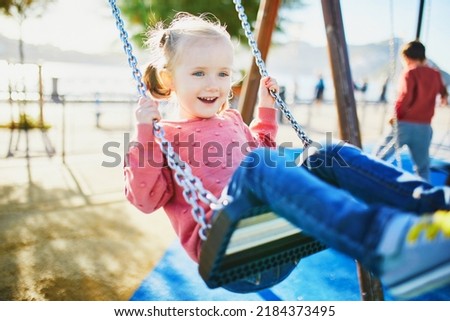 Similar – Image, Stock Photo 4 year old blonde girl with a brightly colored striped sweater sits at a wooden table and draws with a purple pencil on a piece of white paper