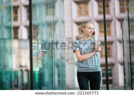Young beautiful business woman in modern glass interior speaking on the phone