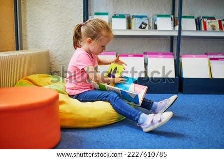 Similar – Image, Stock Photo 4 year old blonde girl with a brightly colored striped sweater sits at a wooden table and draws with a purple pencil on a piece of white paper