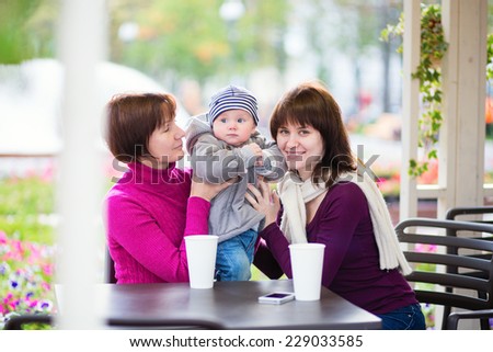 Three generations family - grandmother, mother and little son spending time together in an outdoor cafe