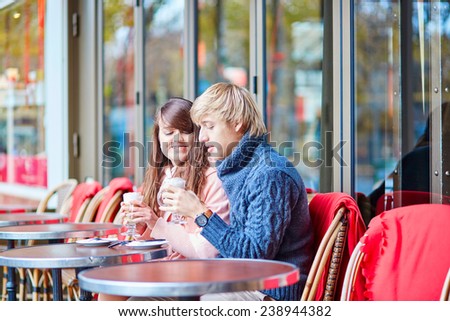 Young dating couple drinking coffee in a Parisian outdoor cafe