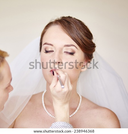 Stylist making up young beautiful bride before wedding