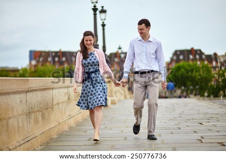 Positive dating couple in Paris walking hand in hand