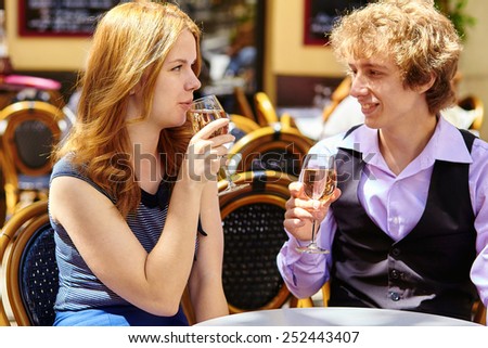 Beautiful couple having a date in a Parisian cafe and drinking rose wine