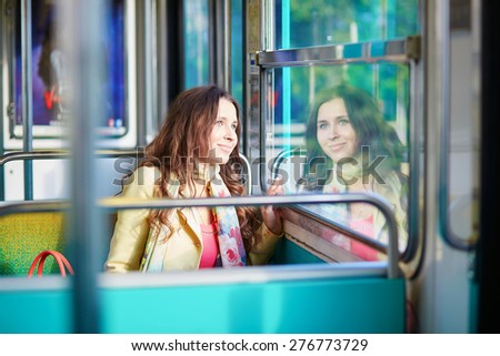 Young beautiful Parisian woman traveling in a subway train, sitting near the window