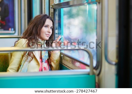 Young beautiful Parisian woman travelling in a subway train, sitting near the window