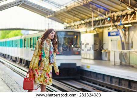 Young beautiful Parisian woman on a subway station, waiting for her train on the platform