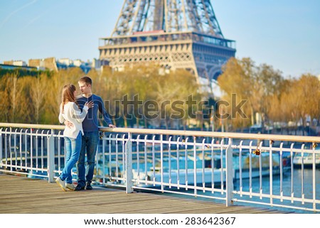 Romantic dating loving couple in Paris hugging on a bridge near the Eiffel tower on a nice spring or summer day