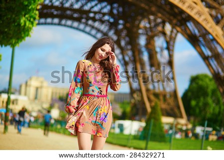 Beautiful young woman walking in Paris under the Eiffel tower on a nice spring or summer day