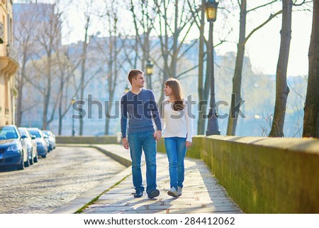 Young romantic couple in Paris, walking together near the Seine