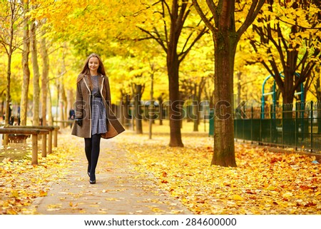 Beautiful young woman in Paris walking in park on a beautiful colorful autumn day