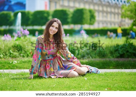 Beautiful young woman in Paris sitting on the grass in park on a nice spring or summer day