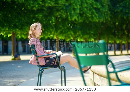 Beautiful young Parisian woman or student reading a book in the Palais Royal garden
