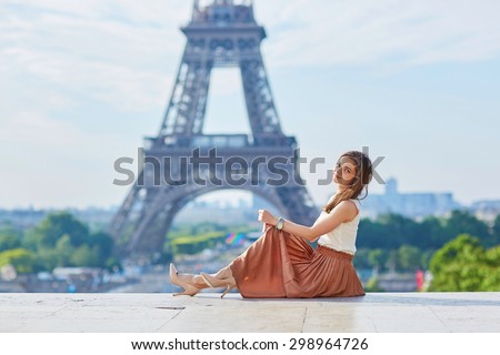 Beautiful young Parisian woman in long brown silk skirt near the Eiffel tower on a summer day