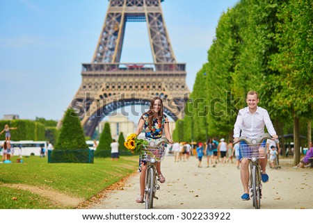 Young romantic couple of tourists using bicycles near the Eiffel tower in Paris, France
