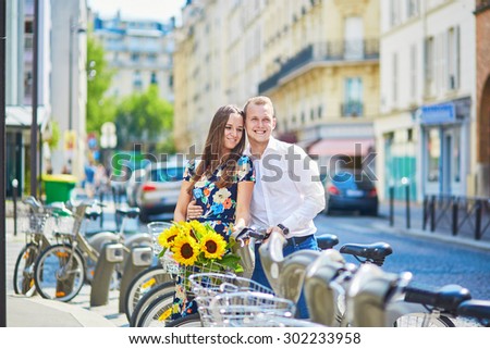 Young romantic couple of tourists using bicycles in Paris, France