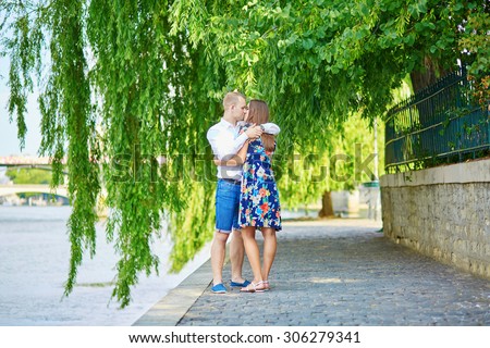 Romantic couple sitting on the Seine embankment on a hot summer day in Paris
